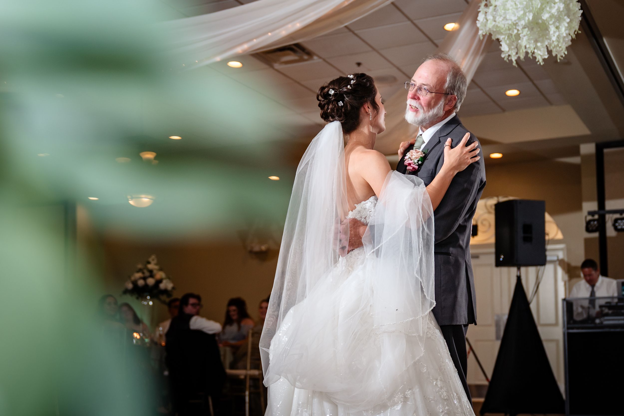 A romantic wedding dance captured in a beautifully decorated reception venue with white draping and soft lighting.