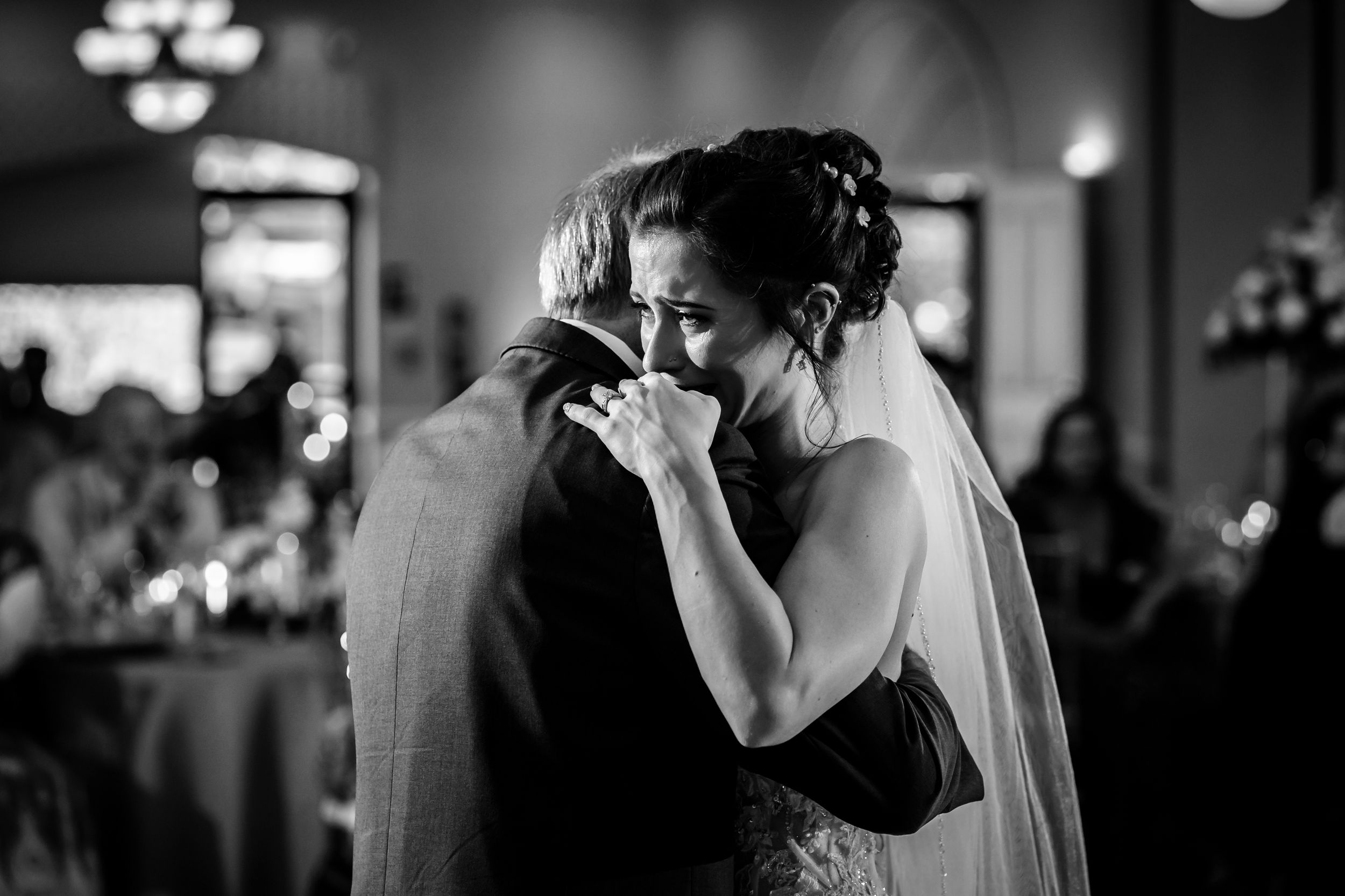 An emotional black and white moment during a wedding dance with the bride in a white gown and veil.