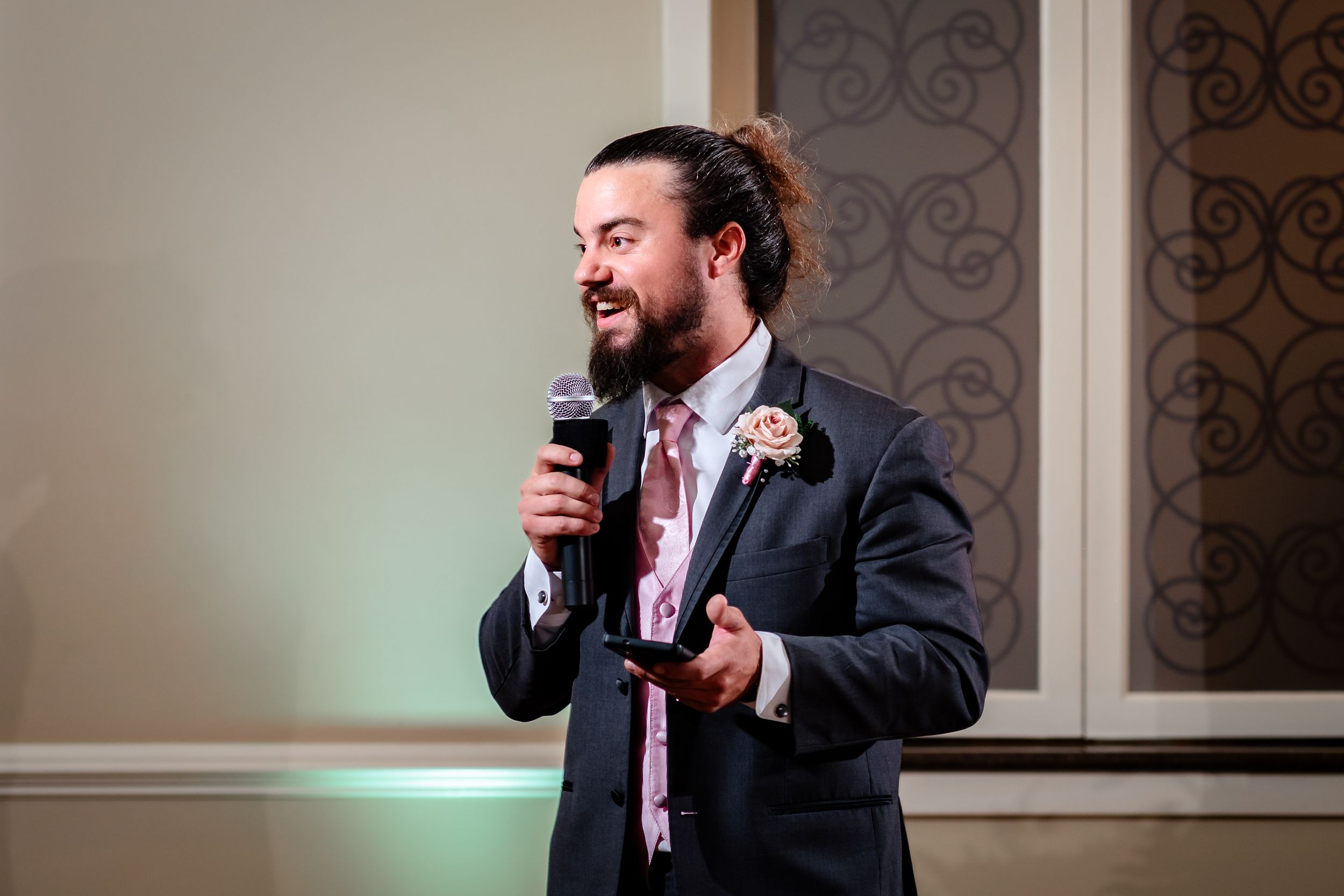 Wedding speech moment captured during reception with decorative wall details and mood lighting.