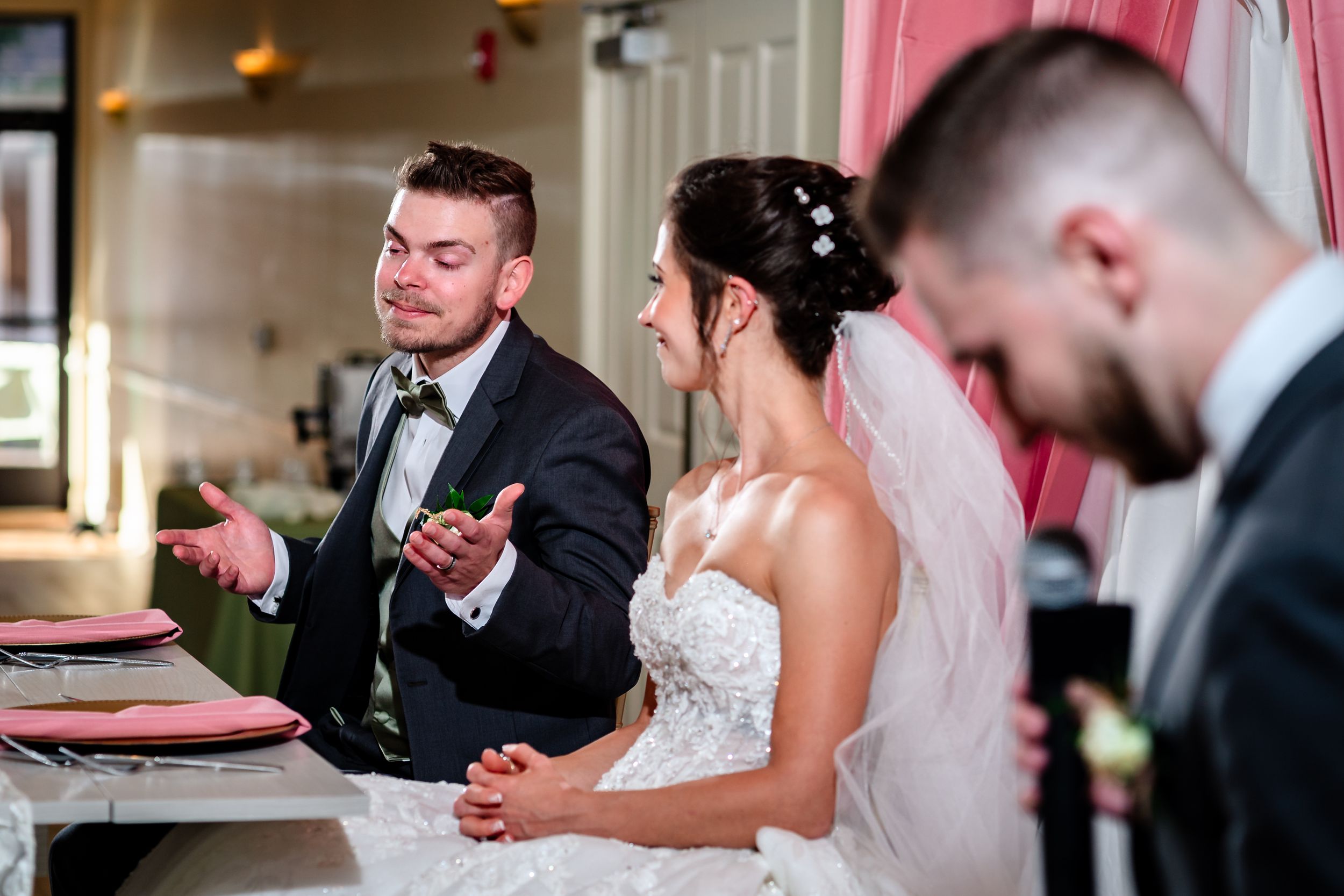 A couple shares a lighthearted moment at their wedding reception table.