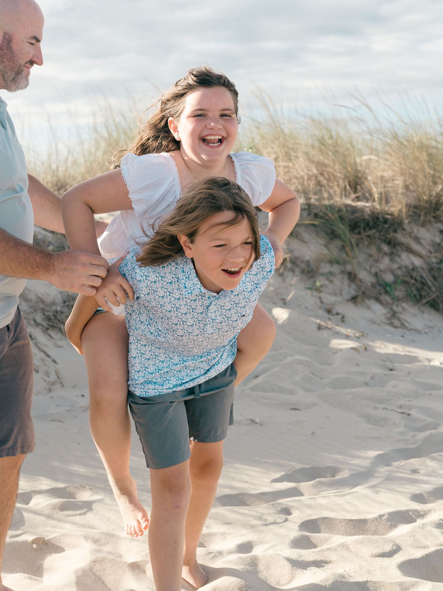 Brother and sister piggy bag ride on the beach in Monmouth County nj.
