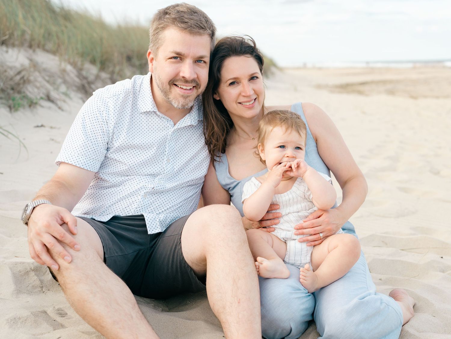 Family with one year old birthday girl pose for pictures on the beach in Monmouth County NJ.