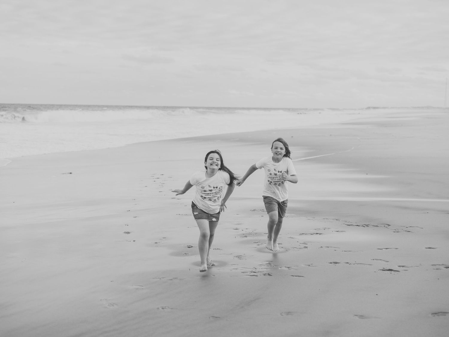 Siblings playing together in the sand during family photo session in Spring Lake NJ.