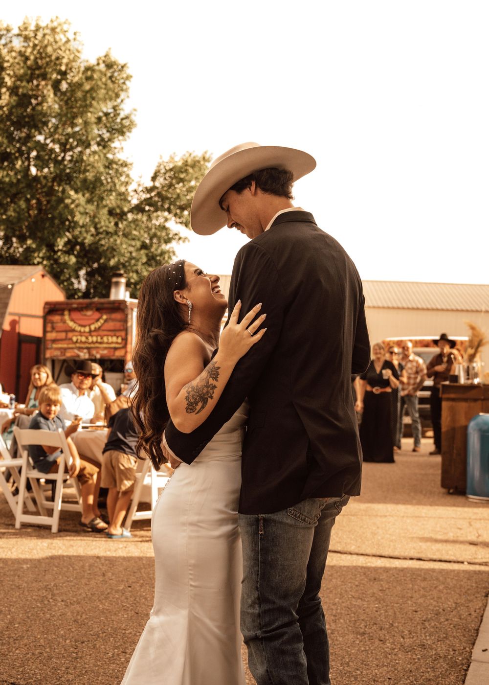 Romantic sunset moment at rustic outdoor wedding reception.