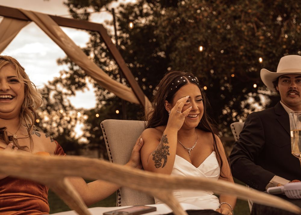 Wedding guests enjoying a festive outdoor celebration under trees at sunset.