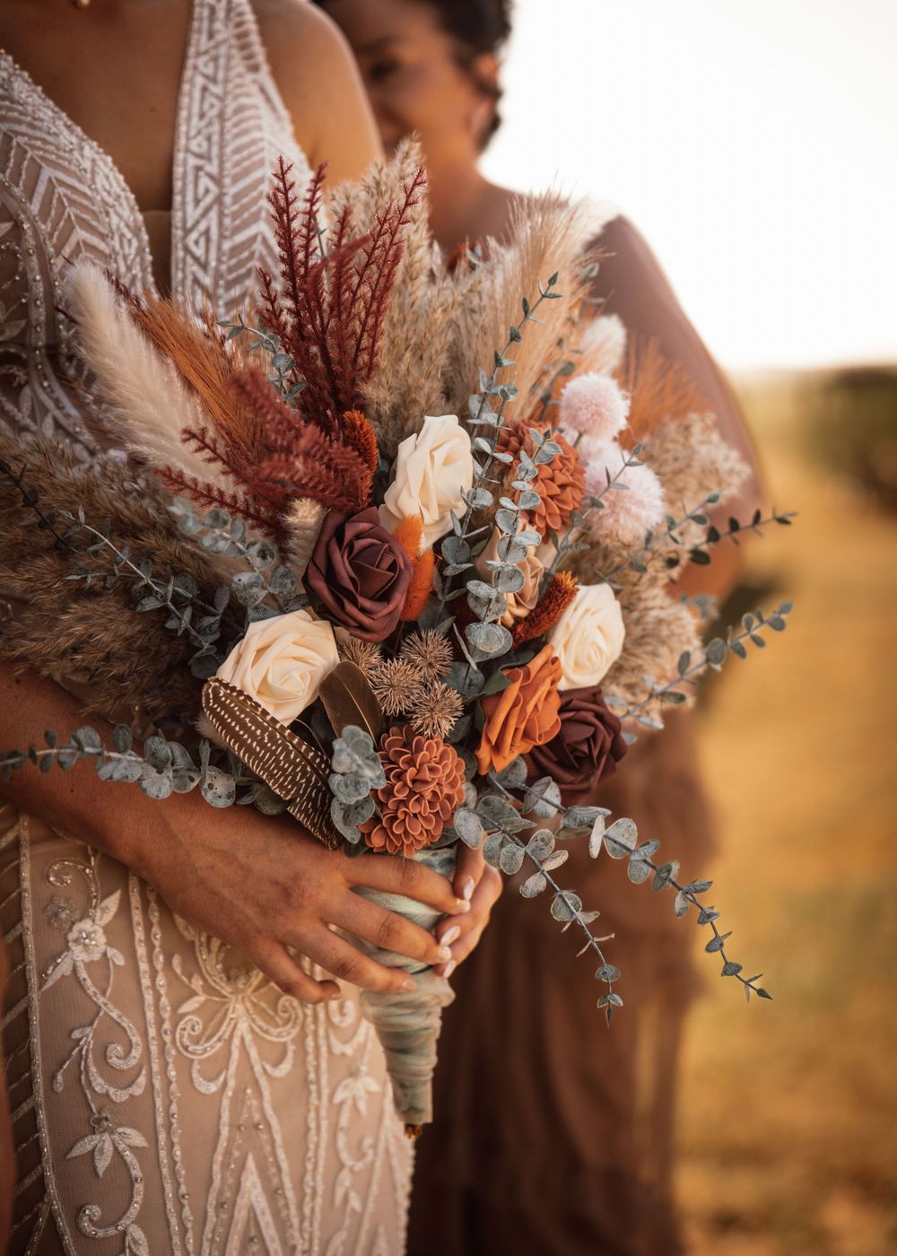 A dried flower wedding bouquet with roses, eucalyptus and pampas grass in muted tones.