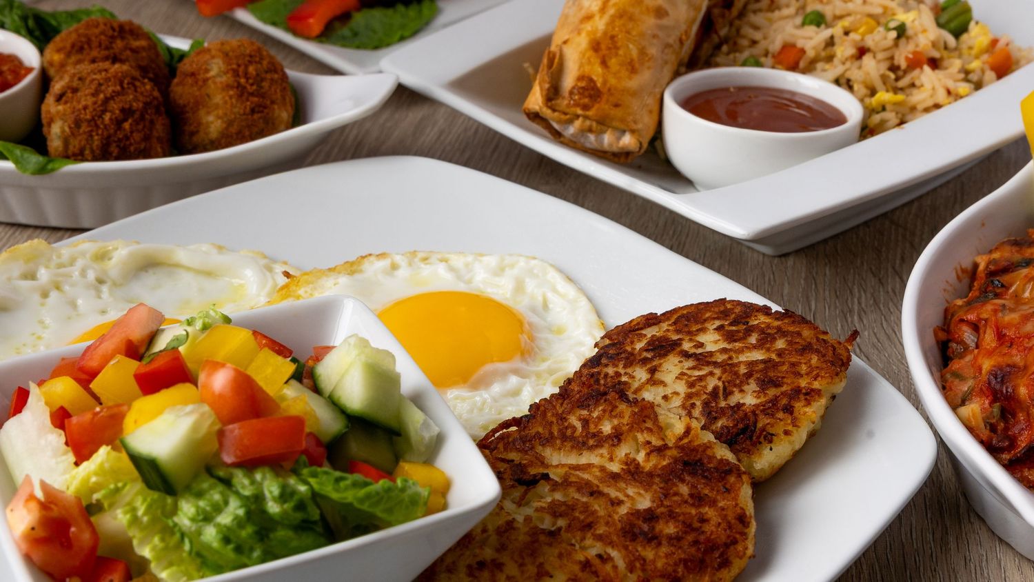 A spread of breakfast dishes including eggs, croquettes, and fresh vegetables.