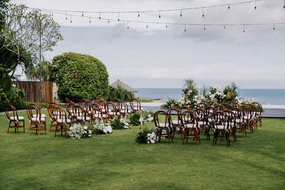 Multiple photos of an elegant seaside wedding ceremony setup with wooden chairs and string lights overlooking the ocean.