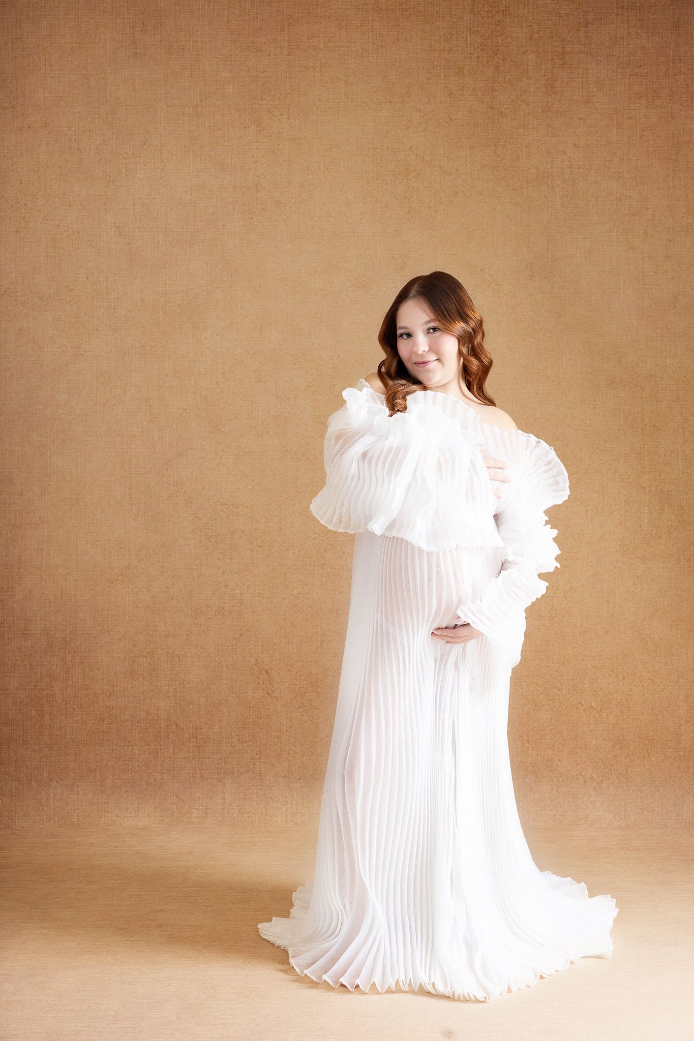 A person in a flowing white pleated dress dances and twirls dramatically against a sepia-toned backdrop.