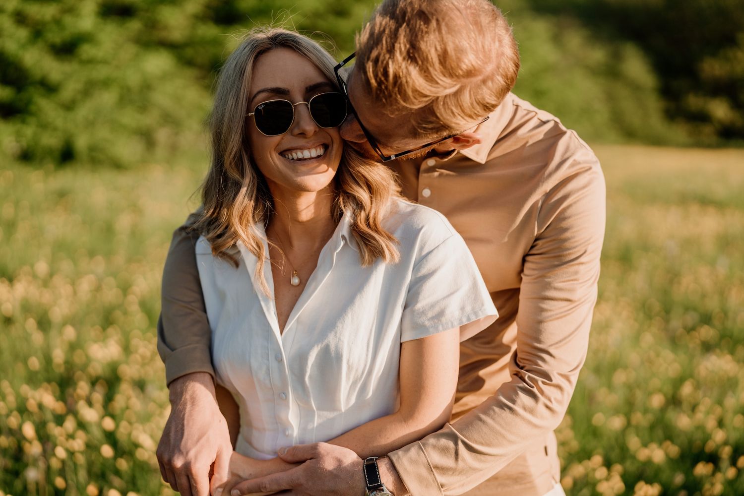 Couple enjoying an intimate moment together in a sunlit field of wildflowers.