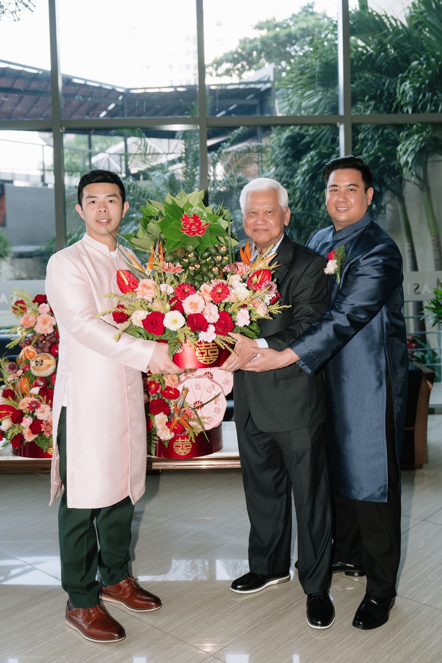 Groom and elder presenting a large floral bouquet at a traditional Vietnamese wedding ceremony.