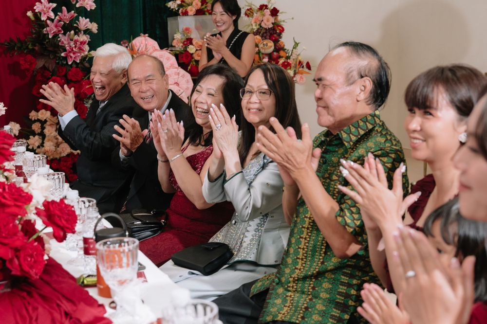 Family members clapping joyfully together at a traditional Vietnamese wedding celebration.