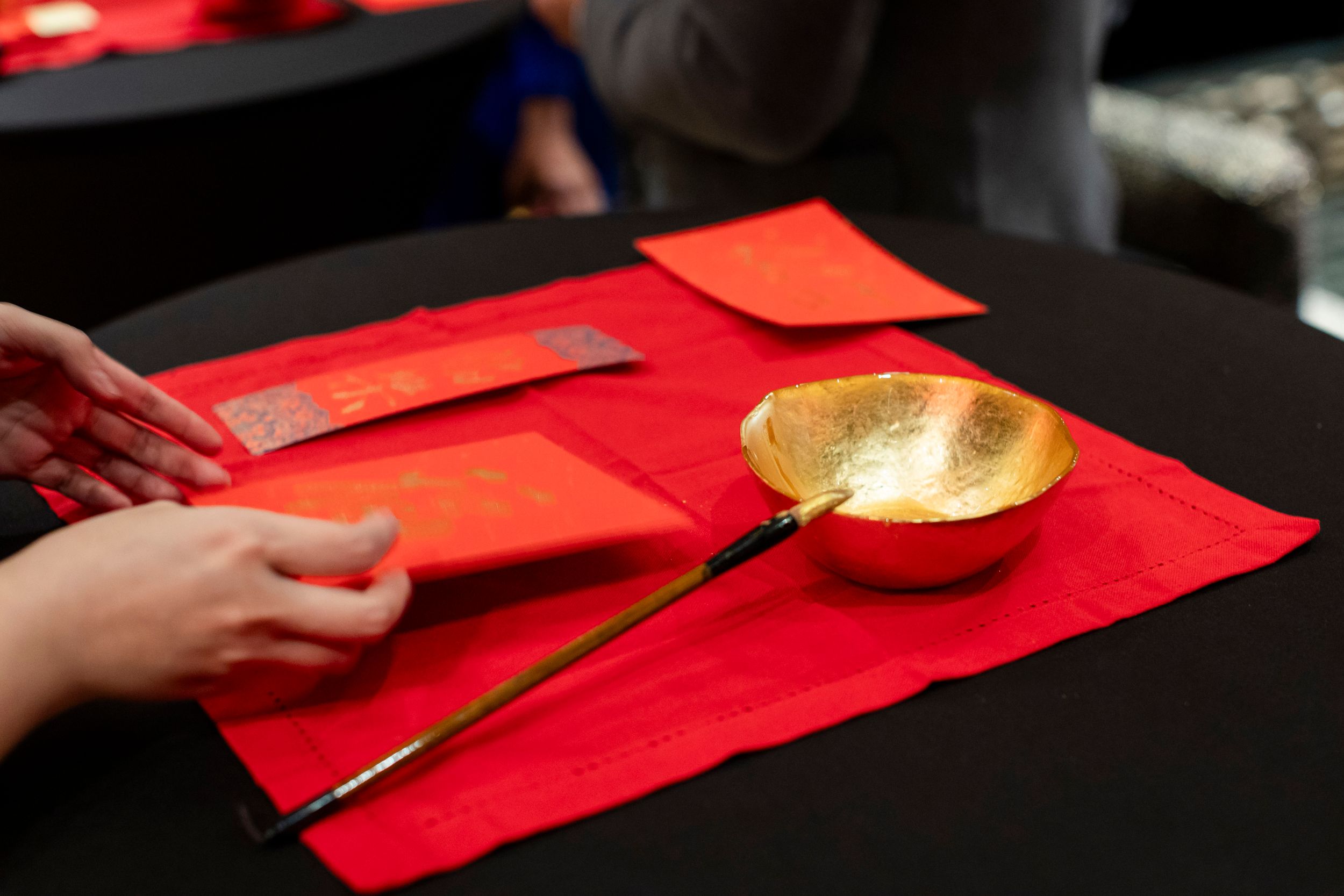 Red envelopes and gold bowl arranged on dark table for Chinese New Year celebration.