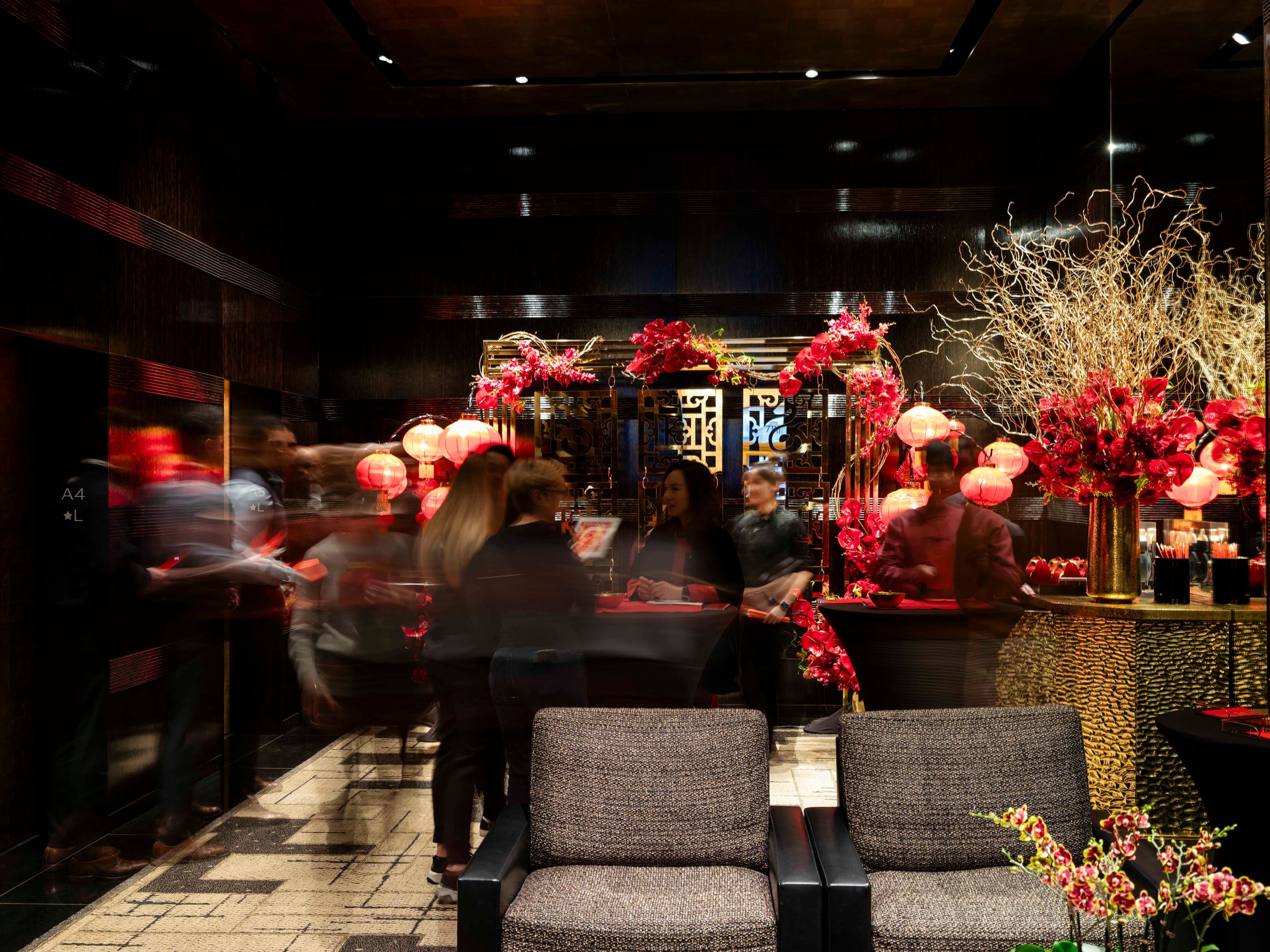 Blurred motion capture of Chinese New Year celebration in dimly lit room with red decorations.