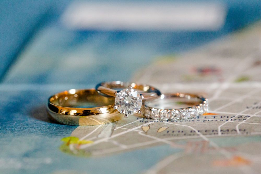 Wedding rings and engagement ring displayed on delicate lace fabric.