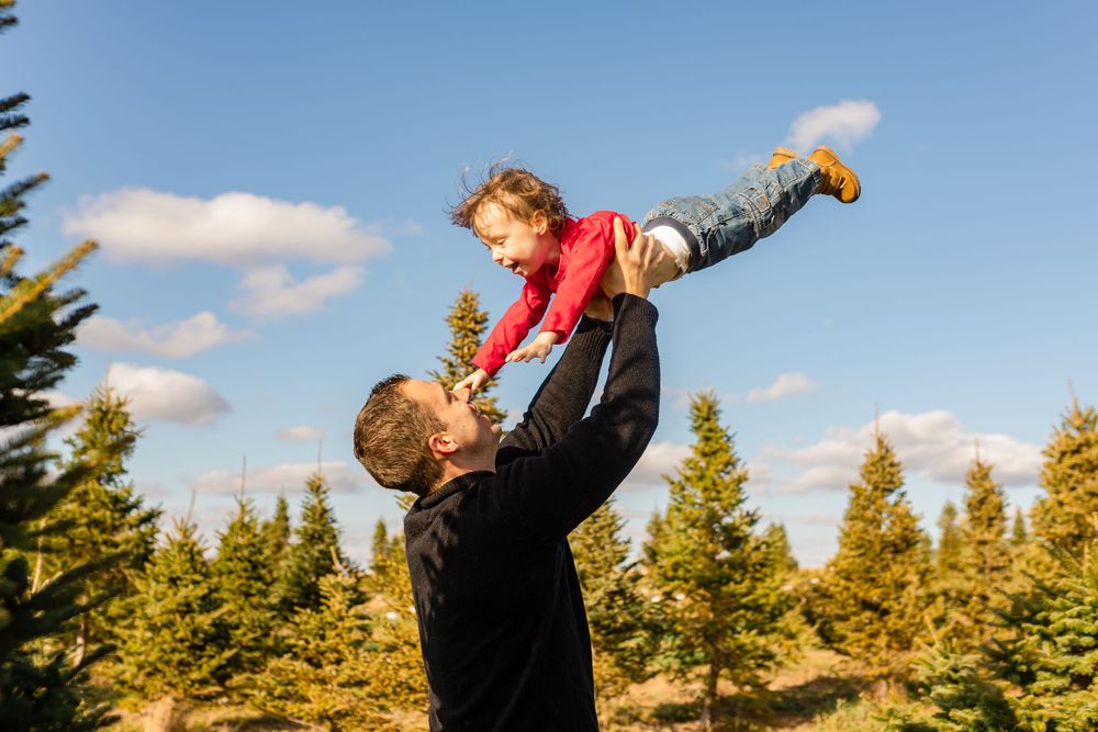 Celebratory moment during a beach wedding with evergreen trees in the background.