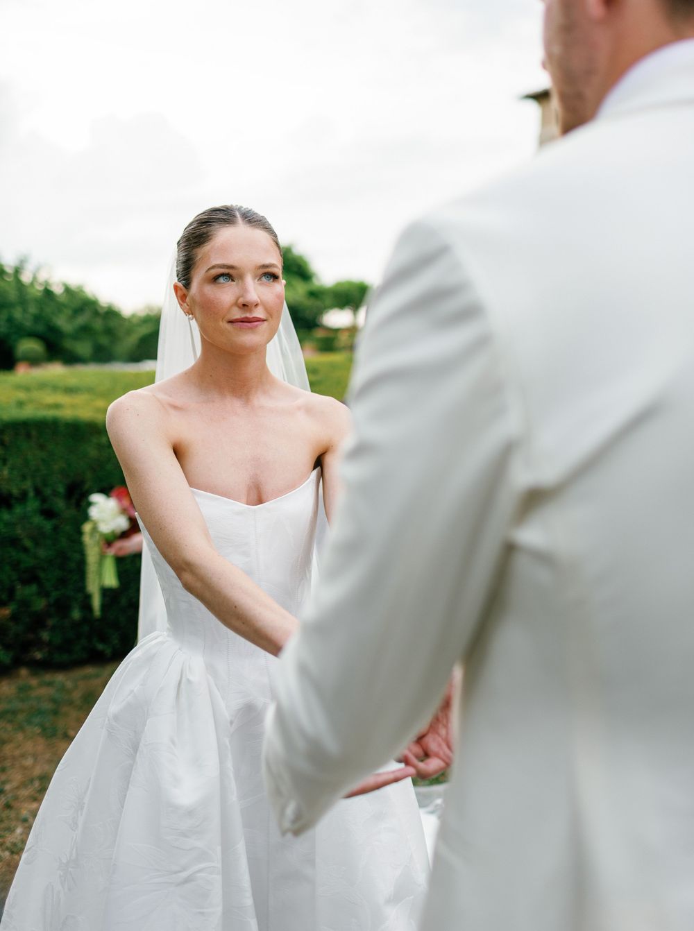 A bride and groom share an intimate dance moment outdoors in a garden setting during their wedding celebration.