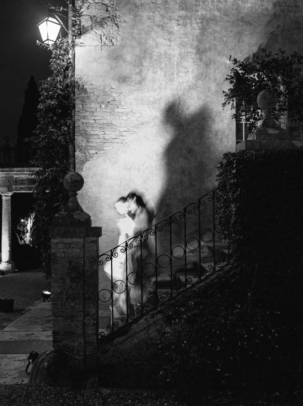 Eerie black and white photo sequence showing a shadowy figure emerging through a foggy lantern-lit garden gate at night.