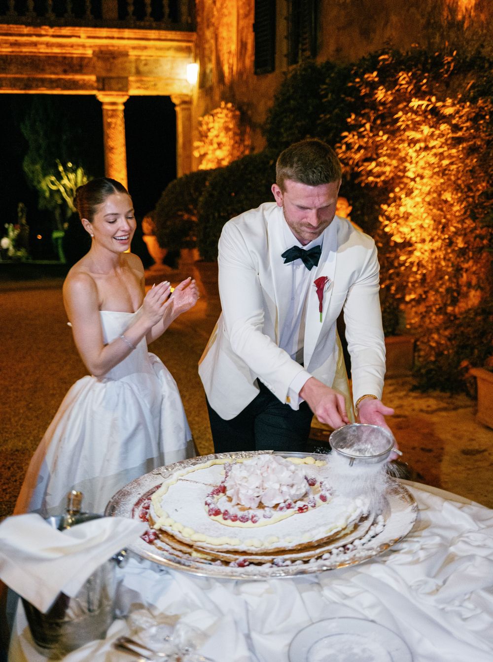 A wedding couple laughing and playfully cutting cake during their reception celebration.