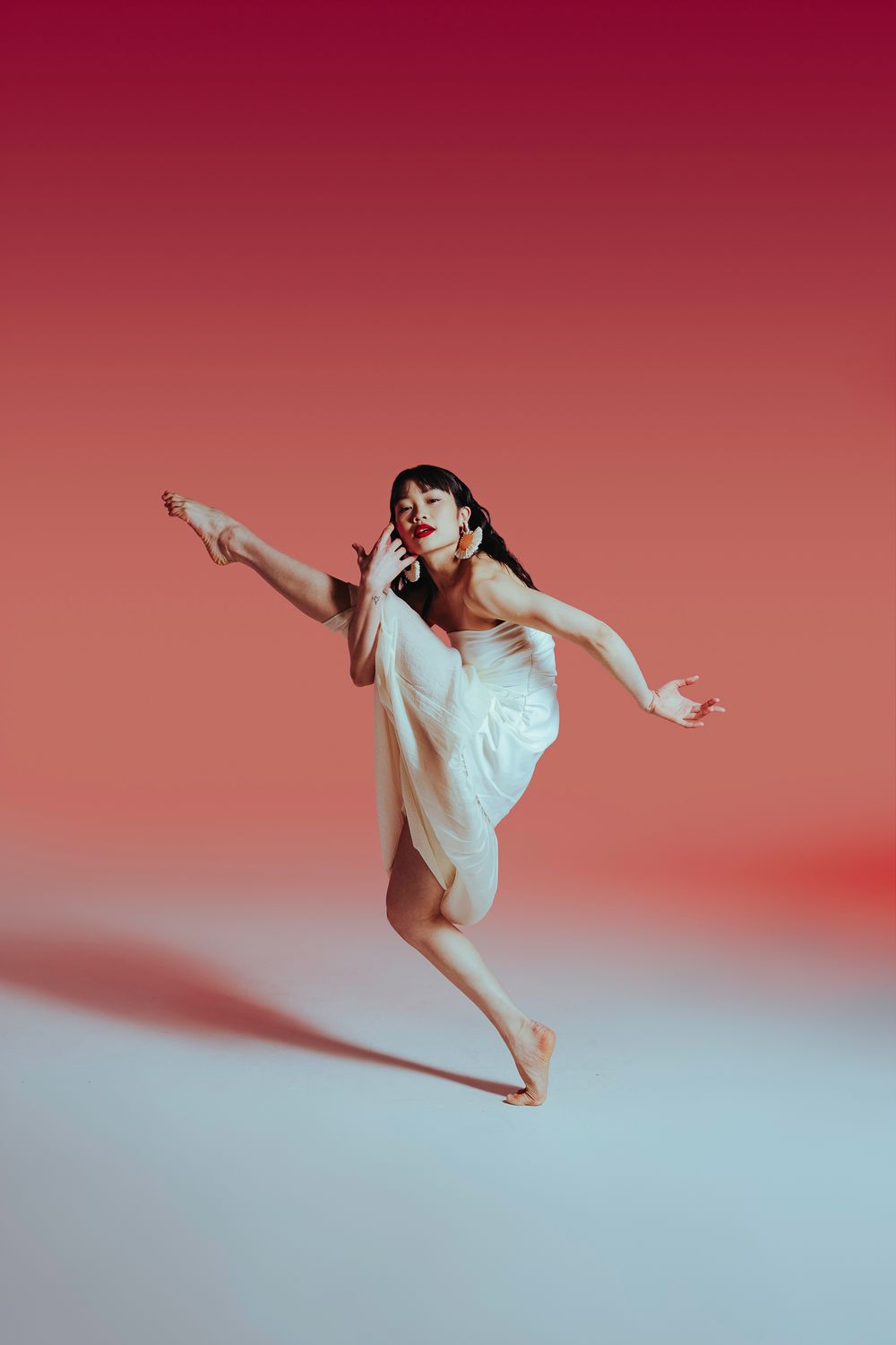 A series of dynamic dance poses shown in sequence with a person in white against a red gradient background.