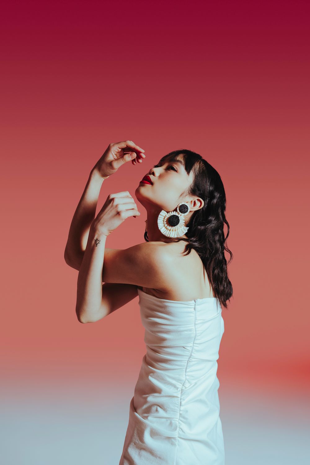 Expressive dance movement sequence showing a performer in white dress against a reddish backdrop.