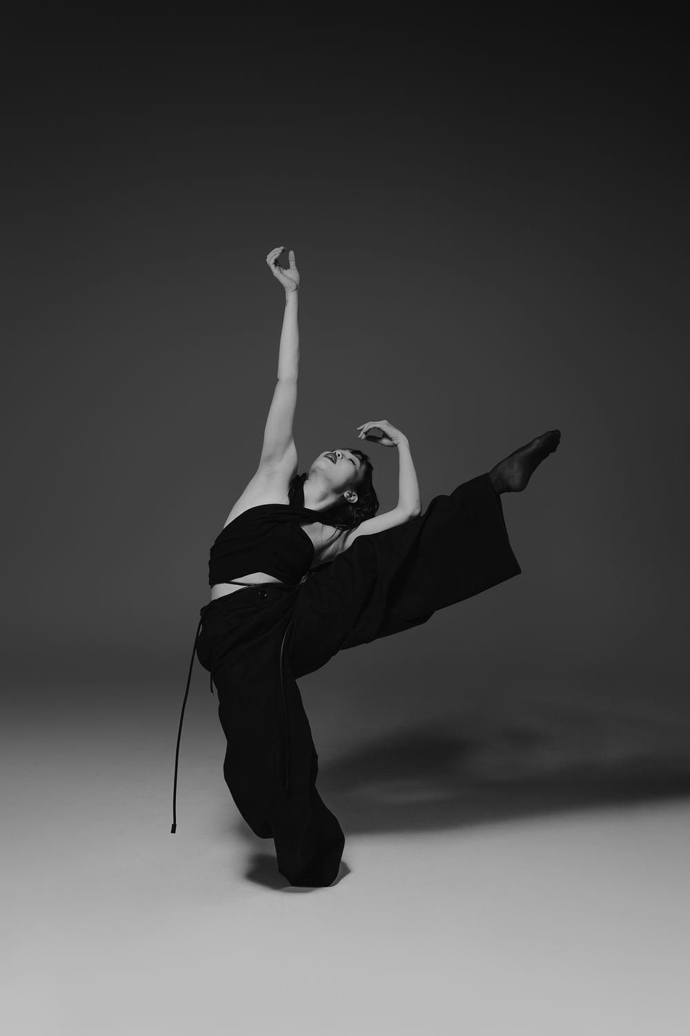 A dancer in black performs a sequence of graceful movements captured in artistic black and white photography.
