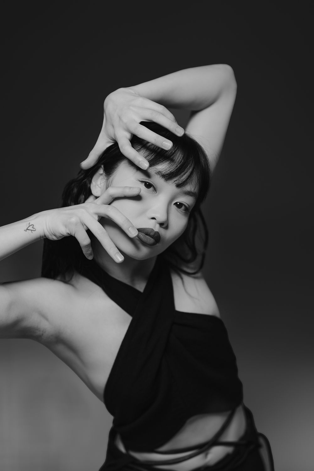 Dramatic black and white portrait photography series showing artistic poses with hands framing composition.