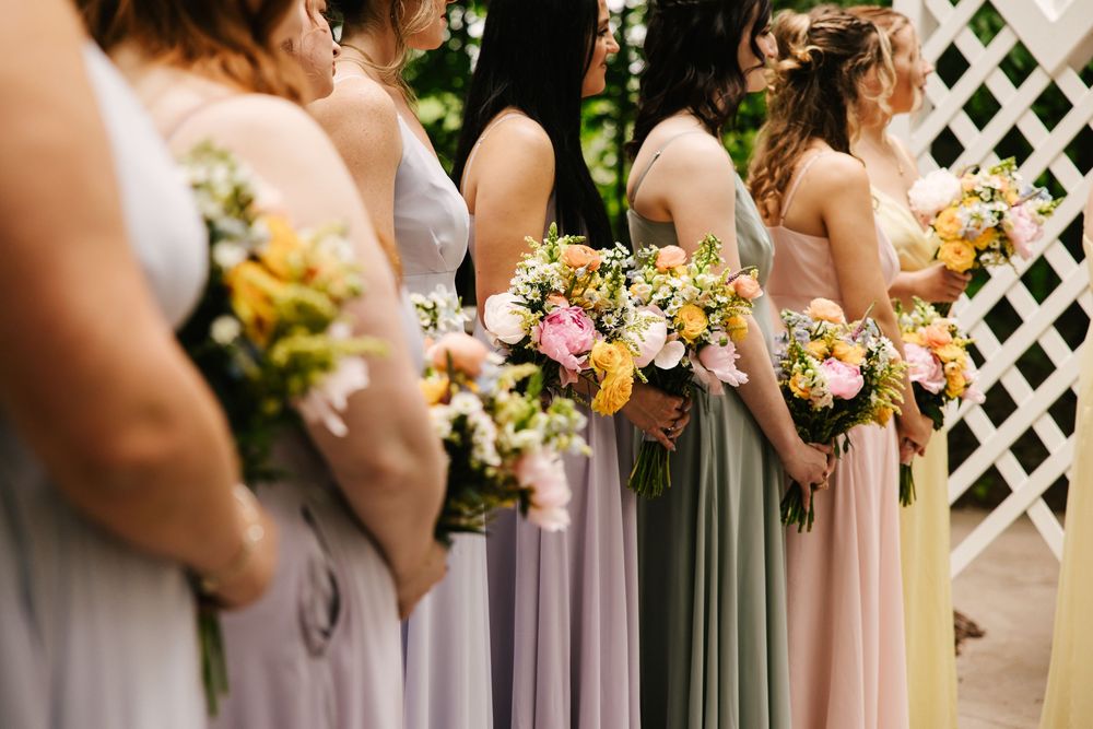 Row of bridesmaids holding bouquets in varying shades of lavender and pink dresses.