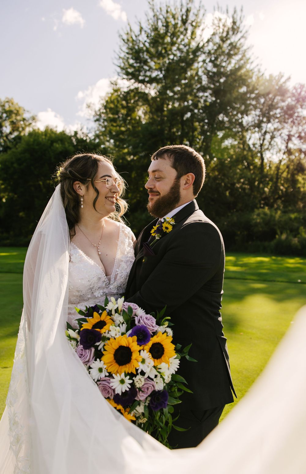 Bride and groom share romantic moments during outdoor wedding photoshoot with sunflowers.