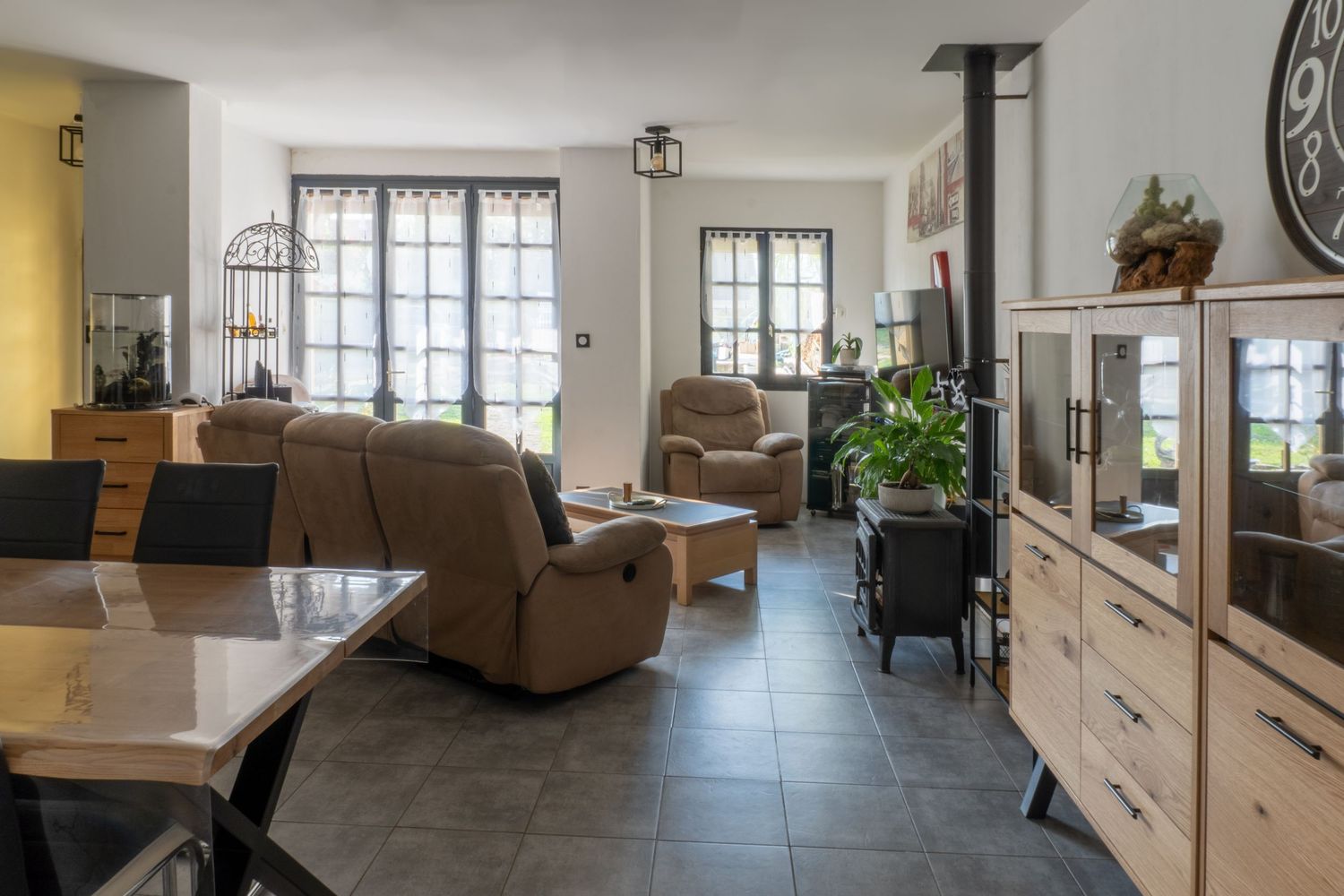 Modern open concept kitchen and living room space with light tile floors and large windows.