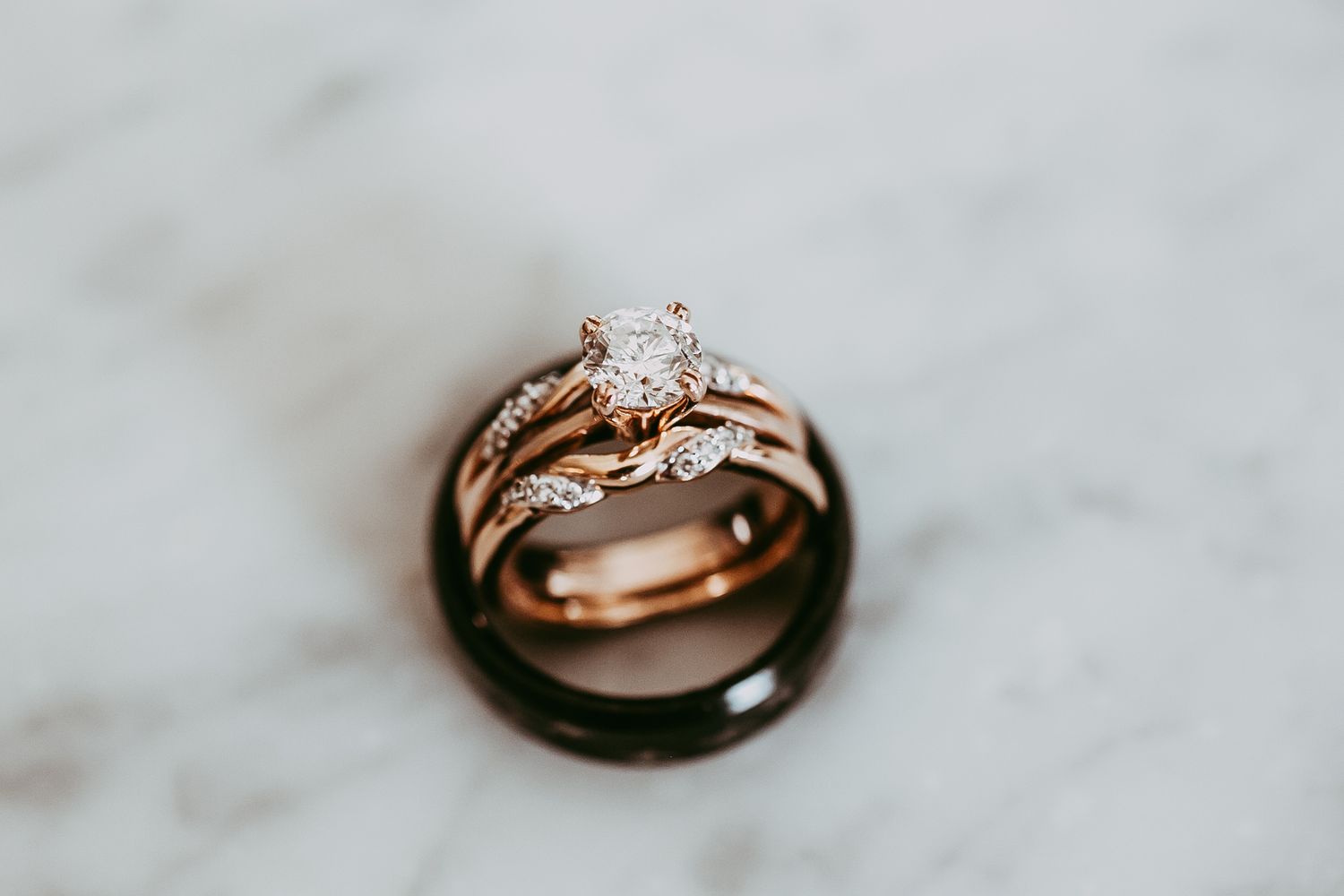 Rose gold wedding rings with diamond solitaire on white marble surface.