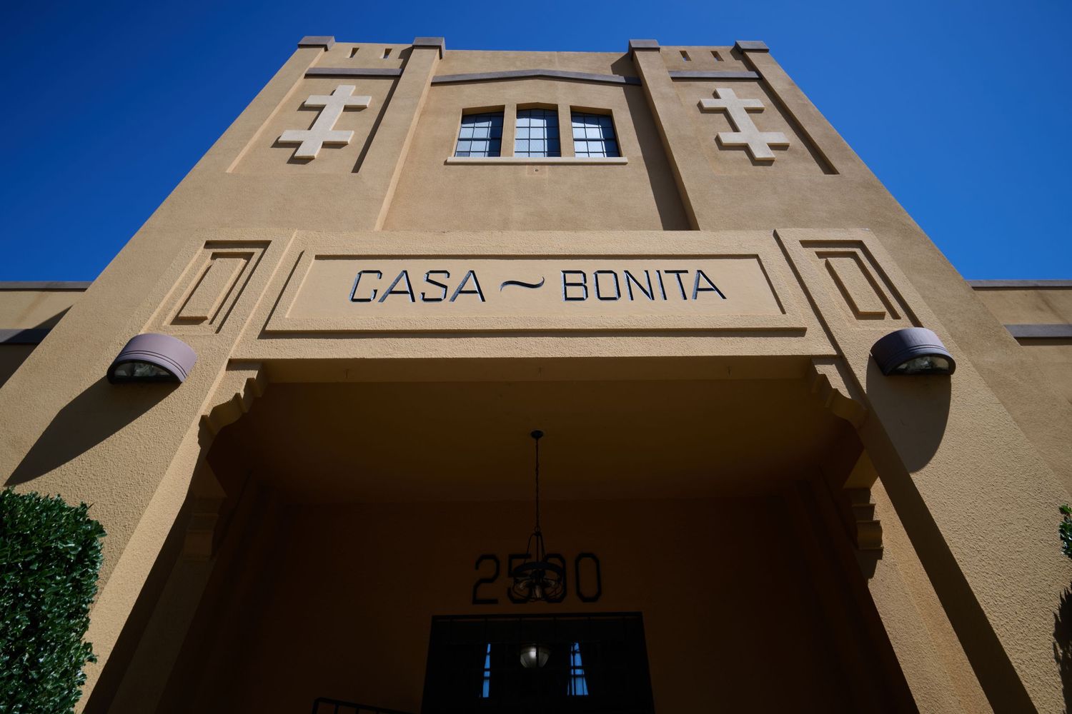 Art Deco facade of Casa Bonita building with tan exterior and geometric details against a blue sky.