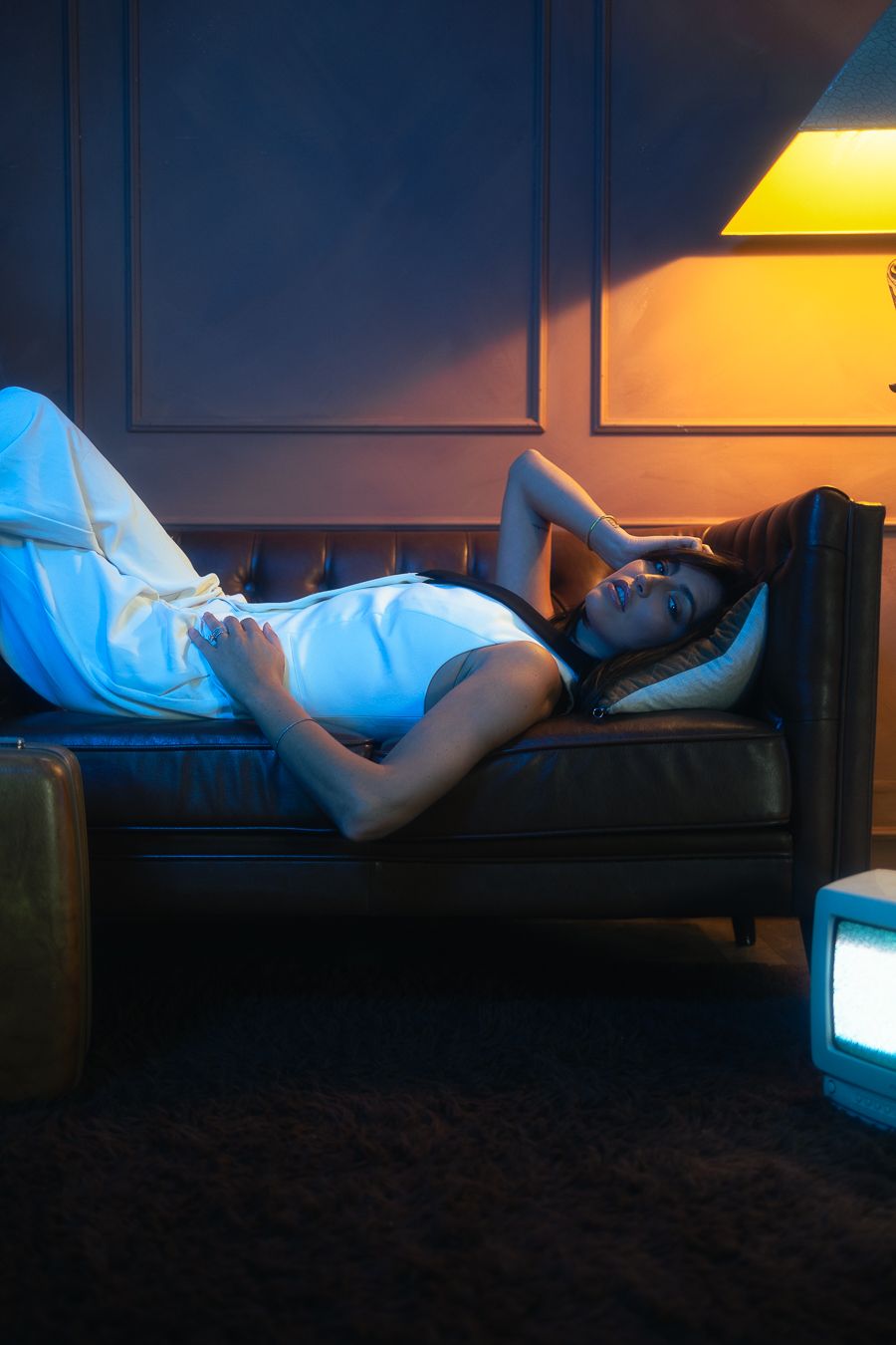 Fashion photography of model in white dress on motel bed, neon cinematic lighting, West Palm Beach editorial by Mannyportraits.