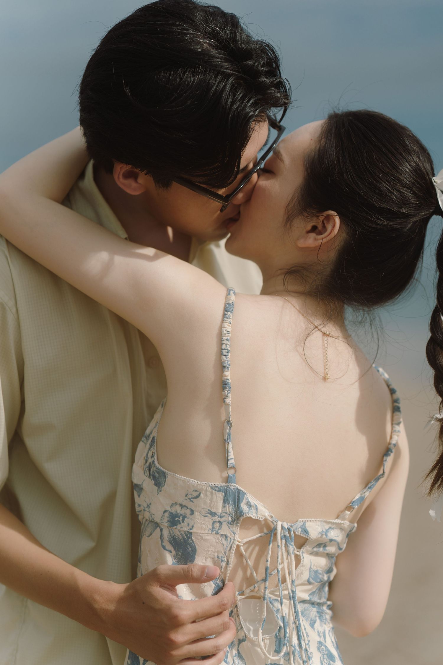 An intimate beach portrait showing gentle embrace against soft natural lighting.