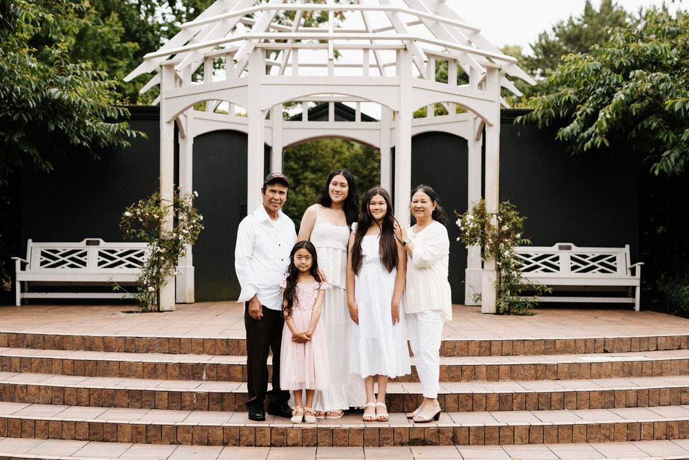 A white gazebo with brick steps surrounded by greenery creates an elegant outdoor setting.