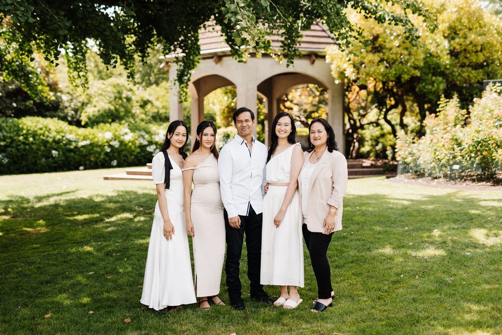 Group stands together on lush green lawn in front of a garden gazebo.
