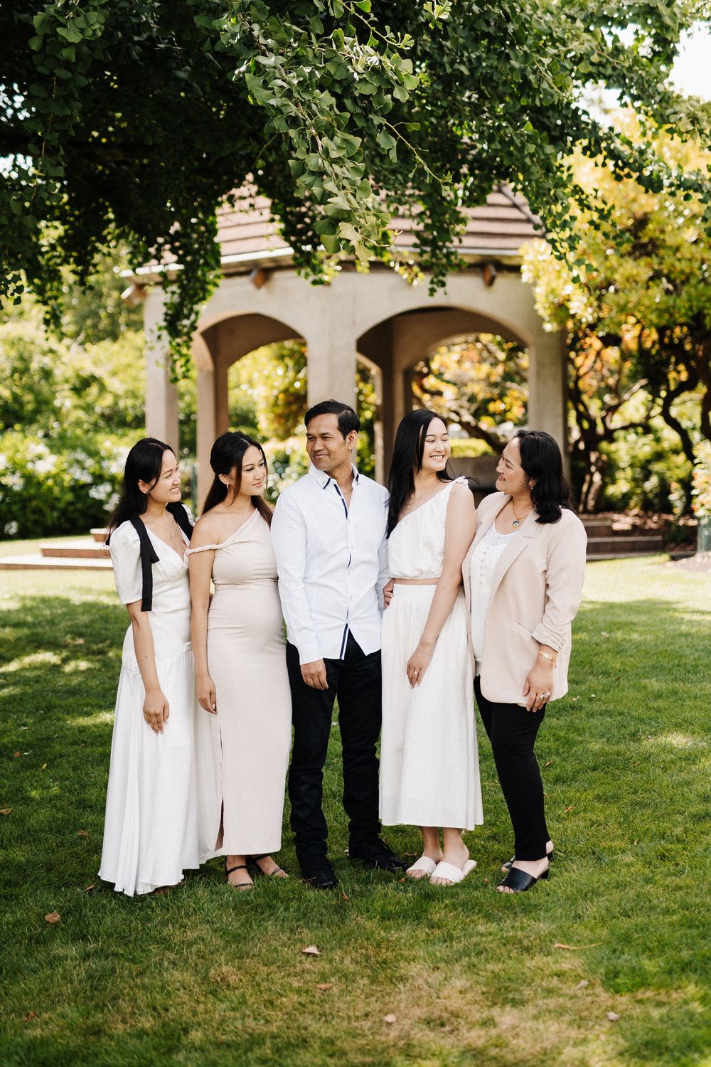 Group photo session on a grassy lawn with people wearing coordinated white and black outfits in a park setting.