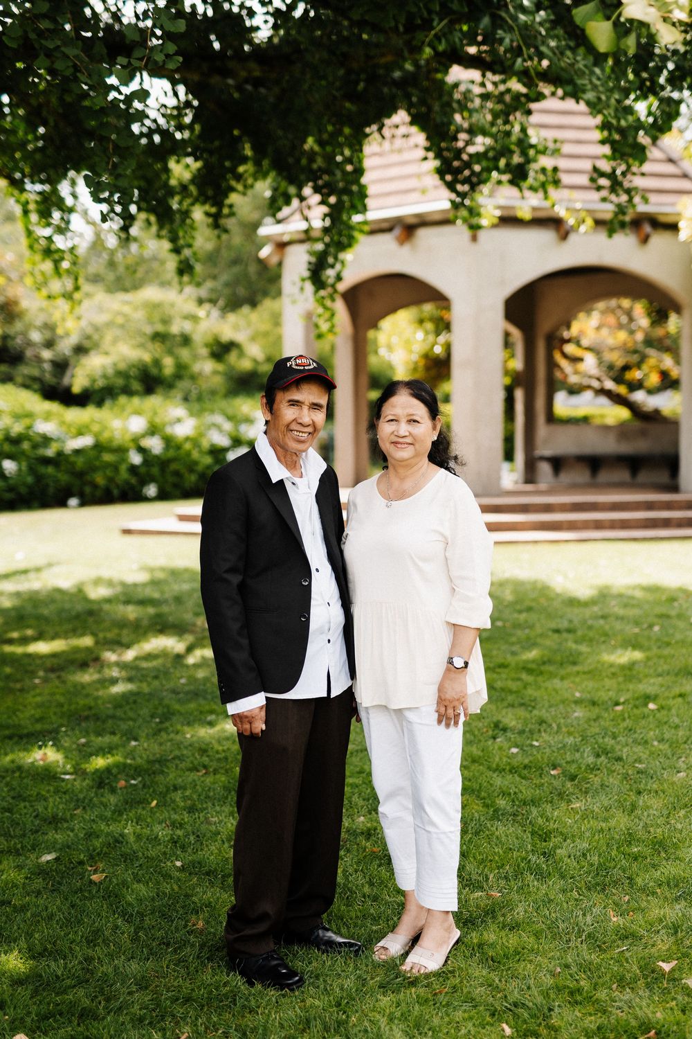 Two people in contrasting black and white outfits stand together on a lush green lawn.