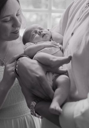 Black and white series showing tender moments between parent and newborn in soft lighting.