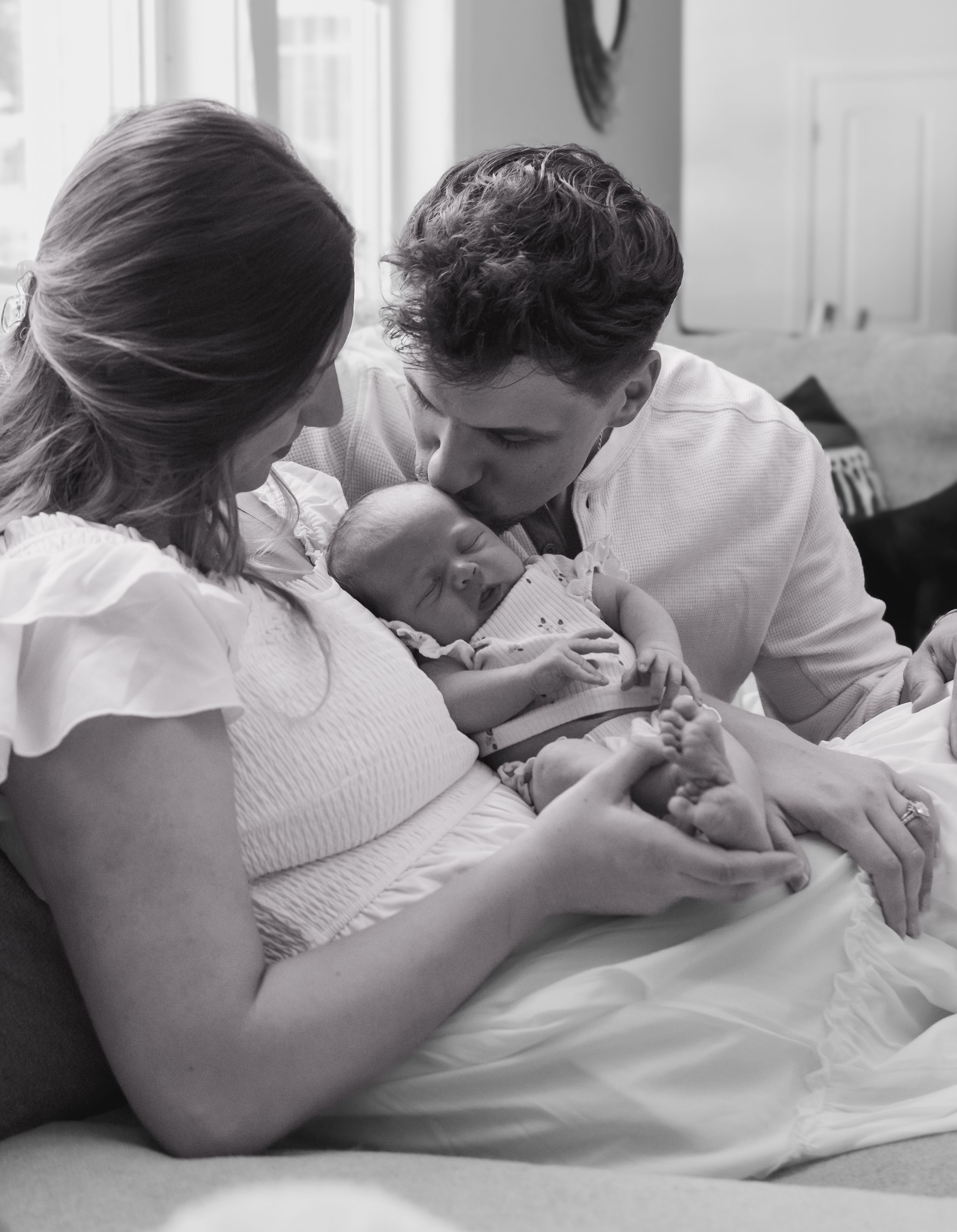 An intimate black and white family moment with a newborn baby.