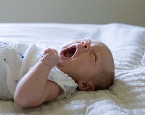 A newborn baby lying on white bedding in various candid poses.