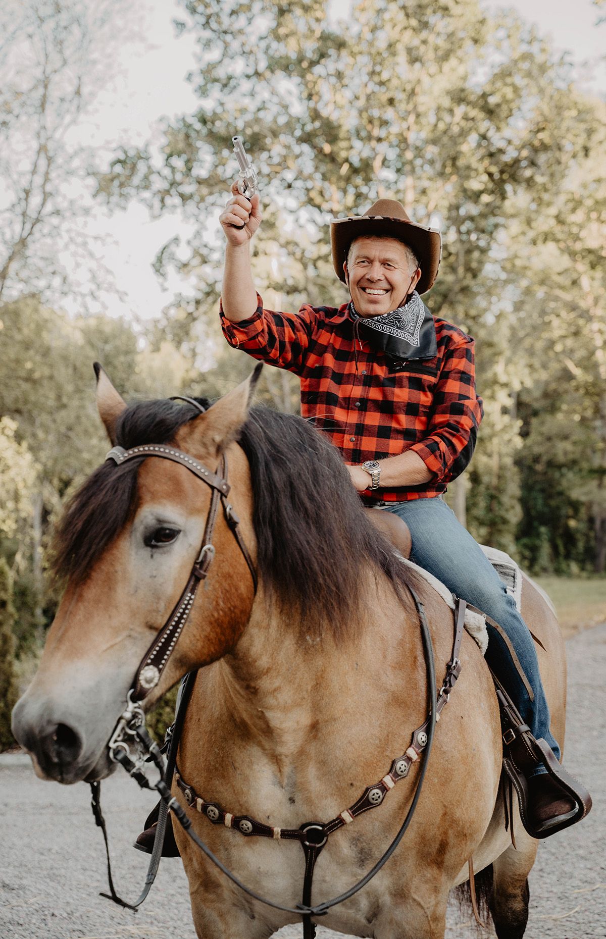En man i rutig skjorta och cowboy outfit sitter på en häst under en temafest i Östergötland, eventfotograf Lets Bloom Media.
