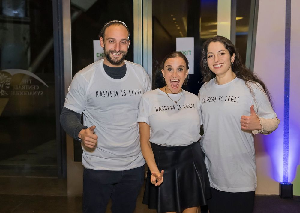 A group in matching gray t-shirts smiling and posing together at an indoor event.