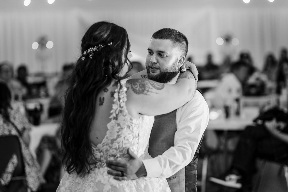 Black and white photo of a couple sharing a romantic moment during their first dance at an elegant wedding reception.