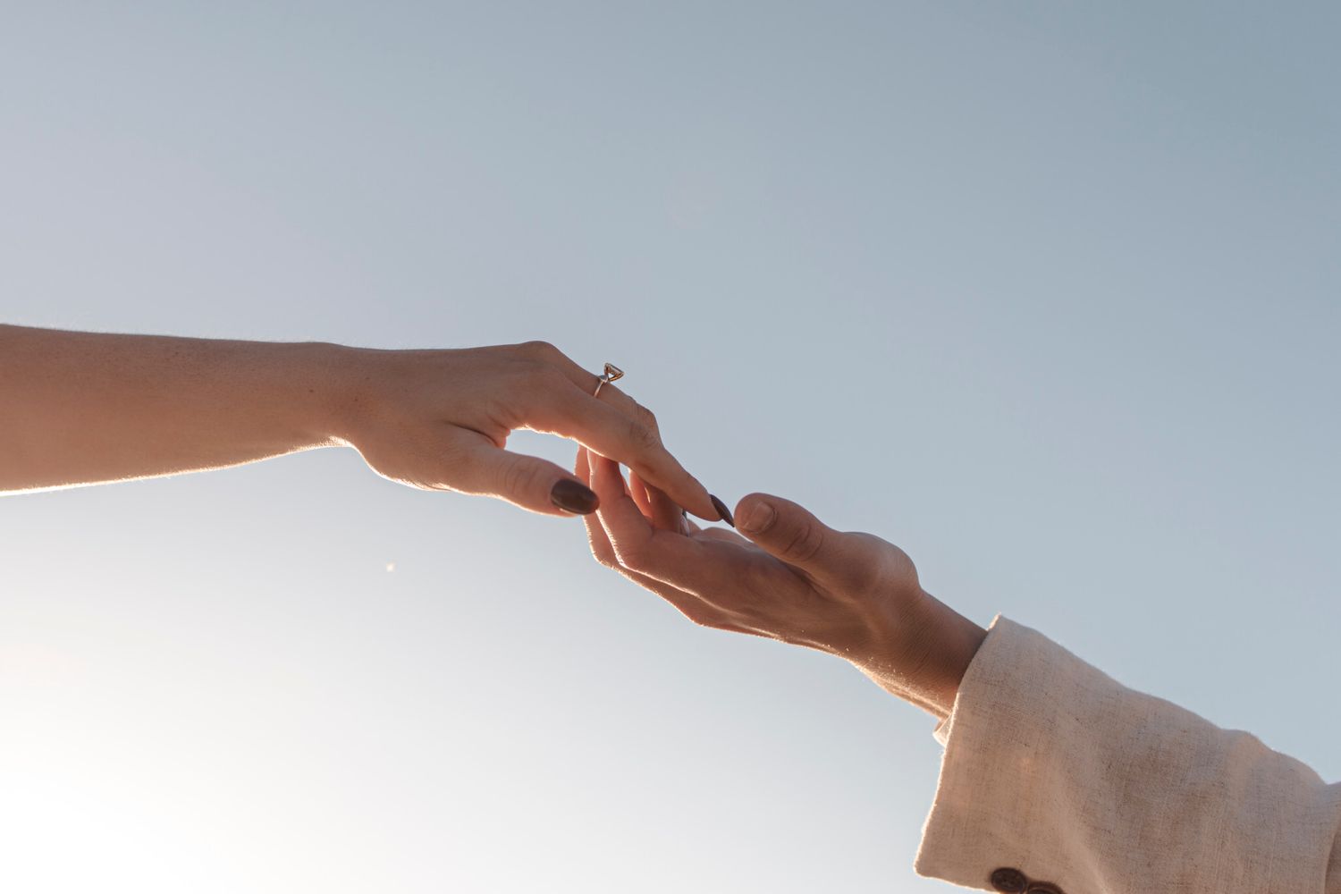 Hands outstretched across a blue sky.Peach and How thoughtful visuals drive conversations. Lumenali Photography.