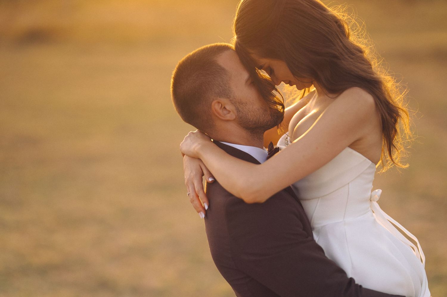 A tender moment between newlyweds captured during golden hour sunset.
