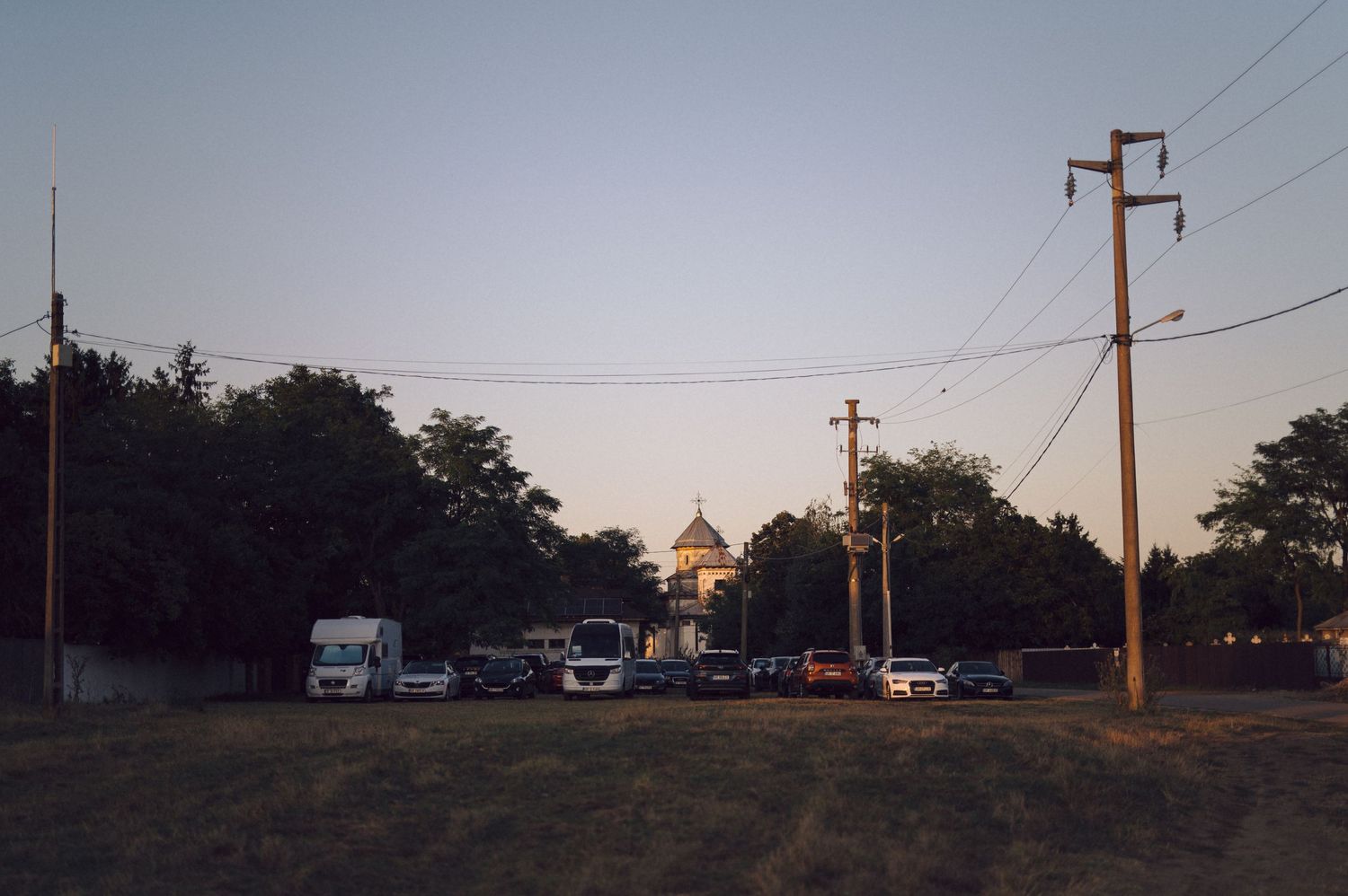 A panoramic view of utility poles and power lines stretching across a rural landscape at dusk.