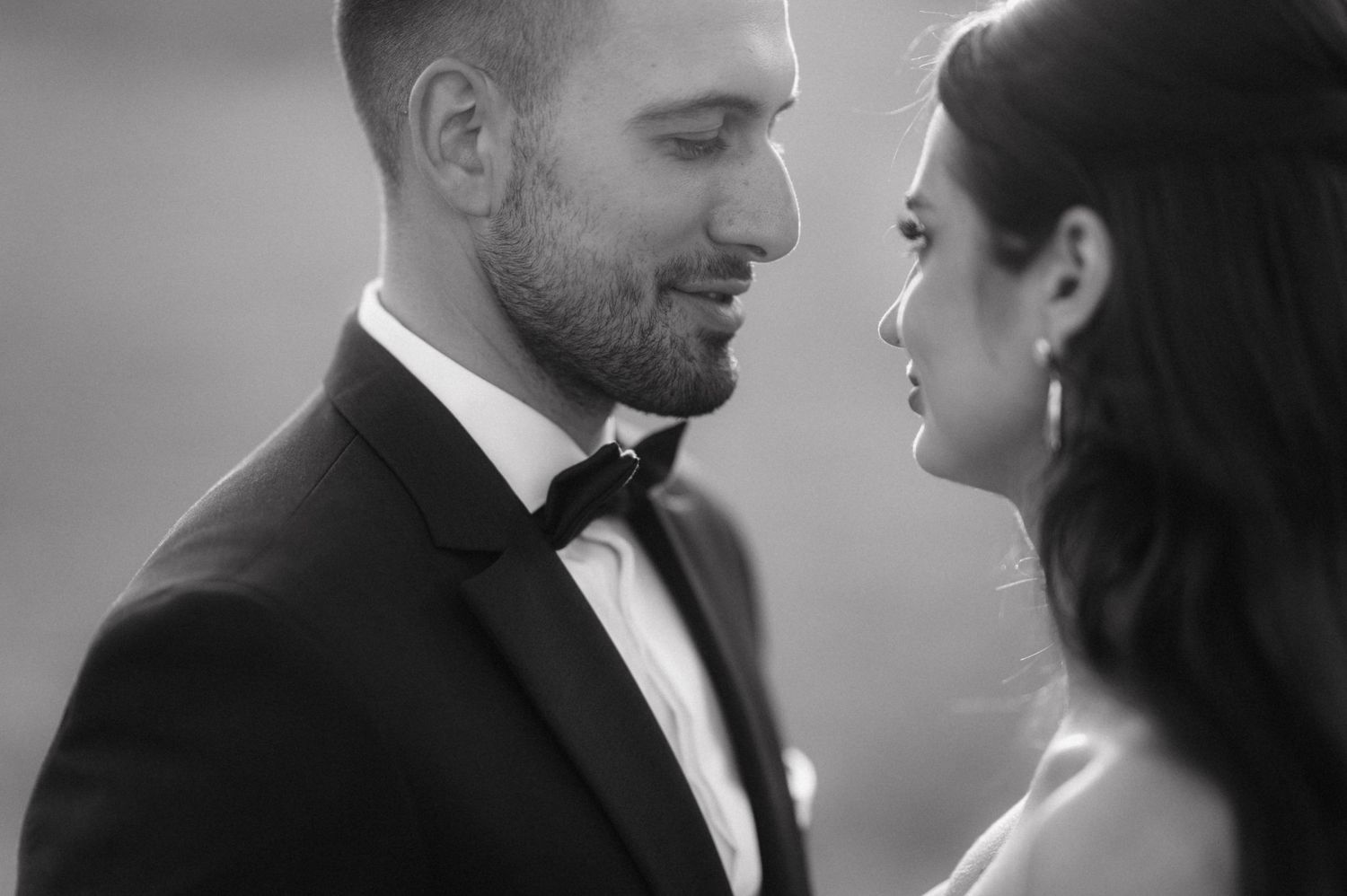 Close-up black and white portrait of couple sharing an intimate moment in formal wedding attire.