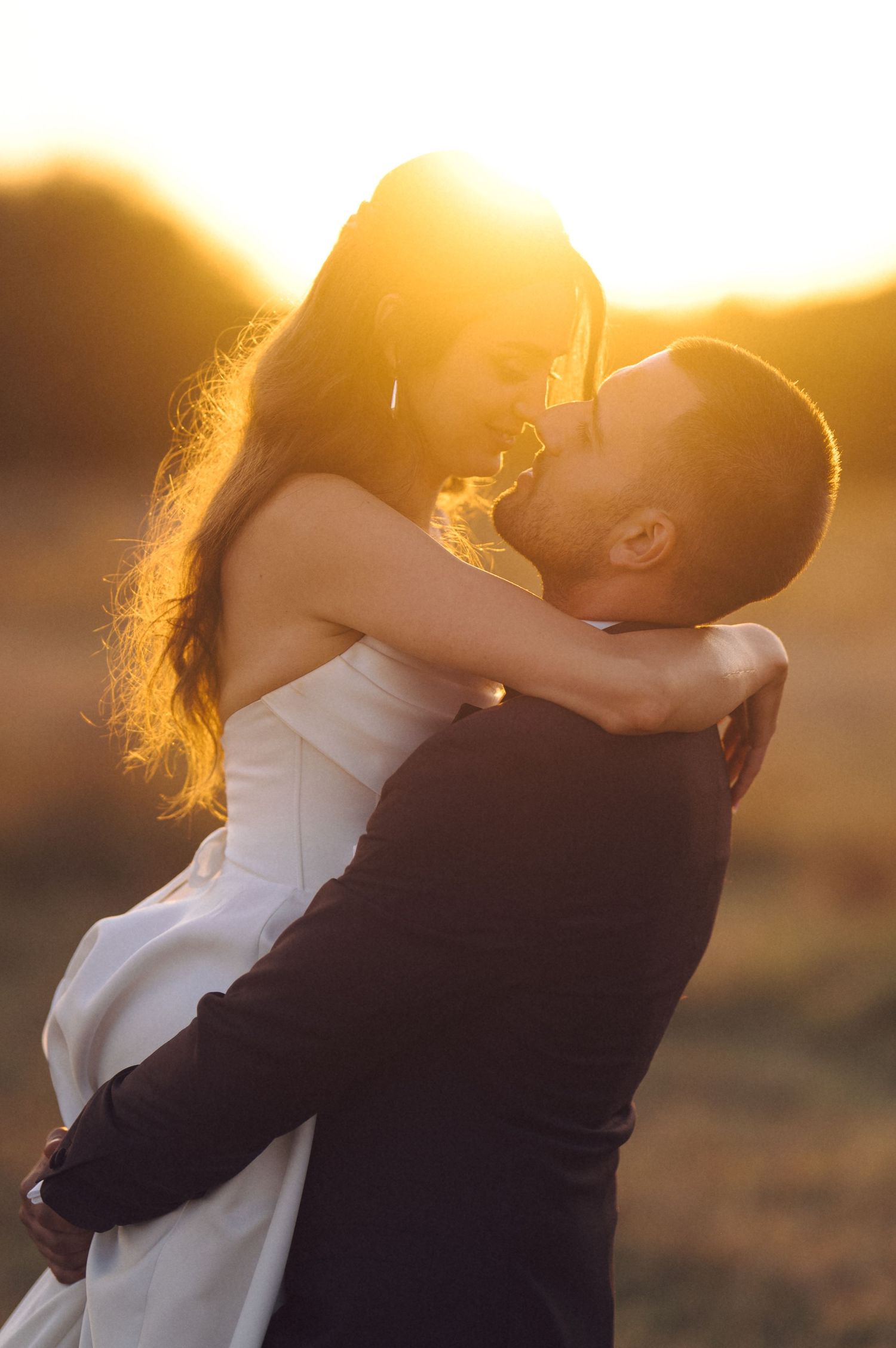 A wedding couple embraces in a golden sunset silhouette sequence creating a romantic atmospheric scene.