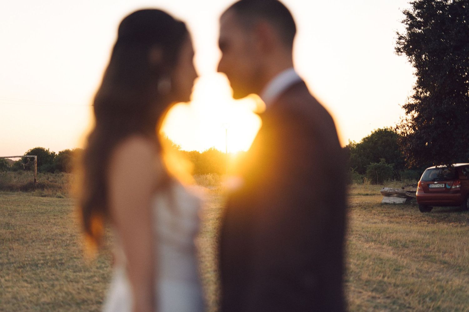 Silhouetted couple embracing during golden hour sunset in an outdoor wedding setting.